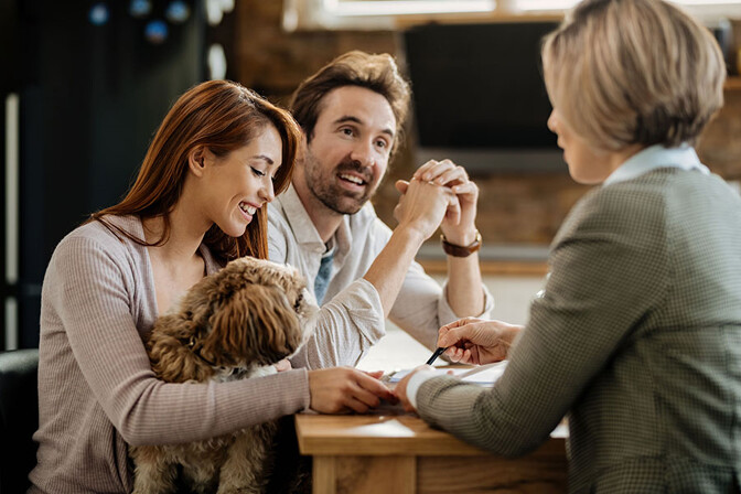 Mann und Frau mit Hunde werden von einer Finanzierungsexpertin beraten