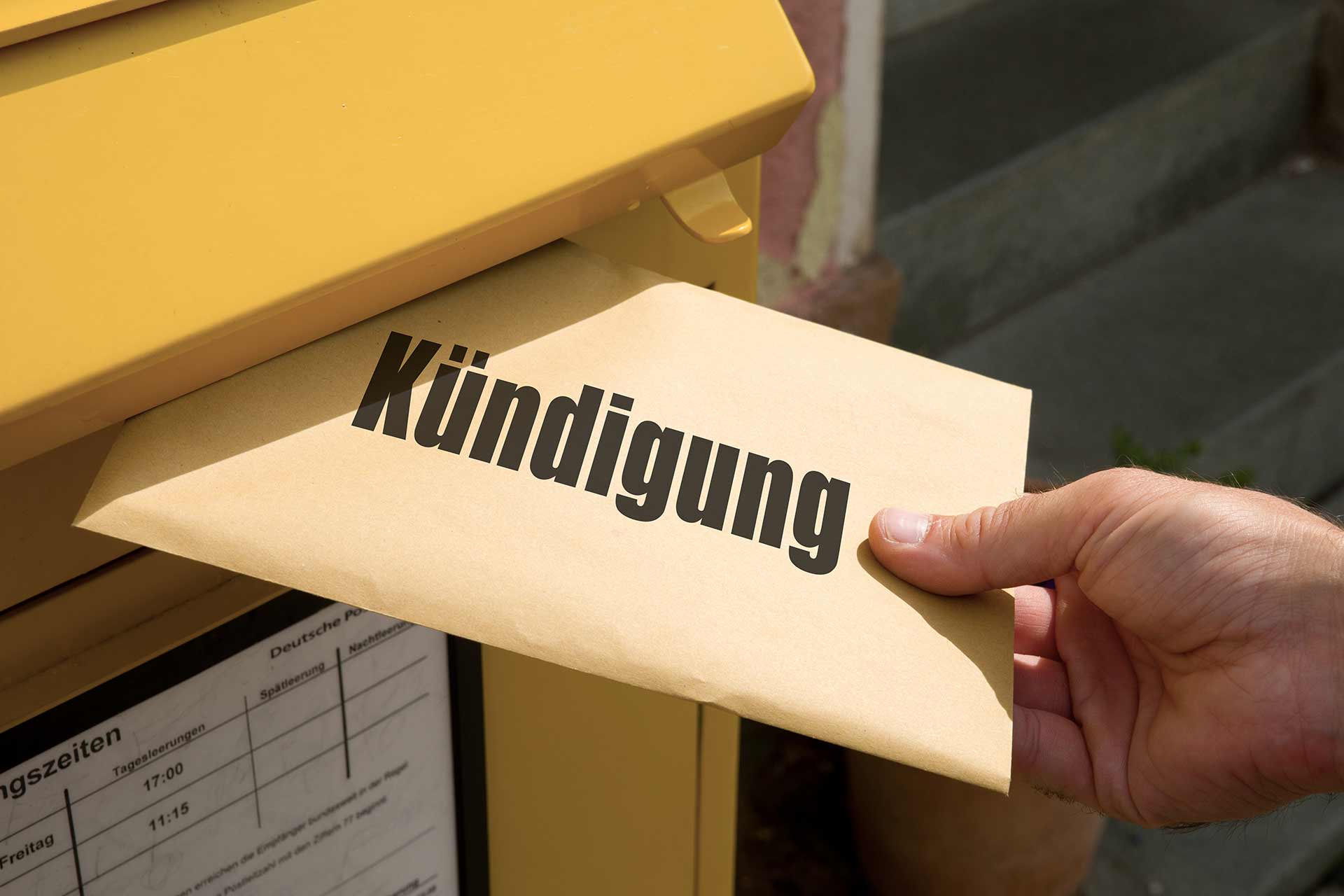 Person wirft Umschlag mit Aufschrift 'Kündigung' für die Wohnung in einen Briefkasten