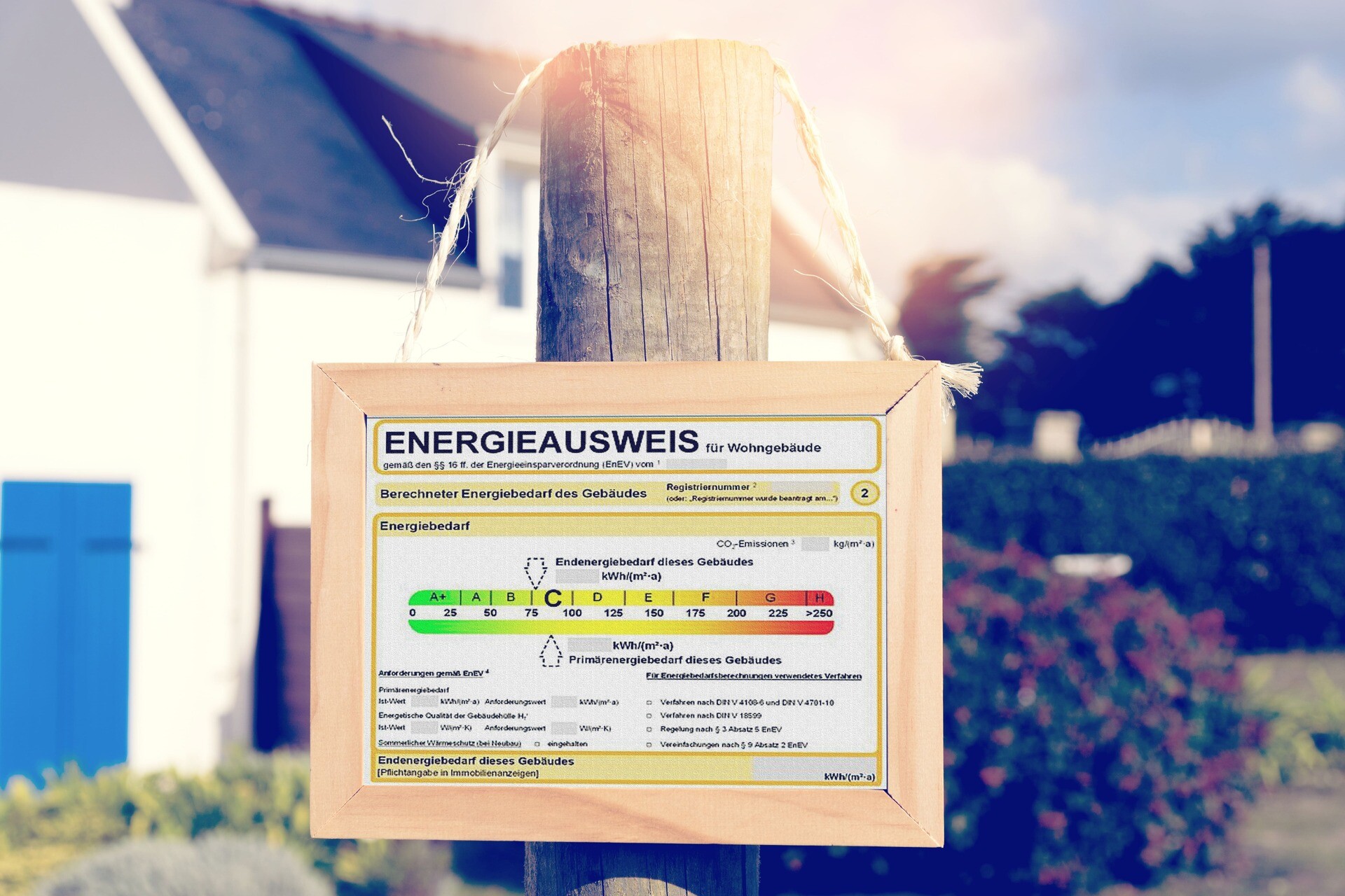 Ein Energieausweis hängt an einem Pfahl vor einem Haus