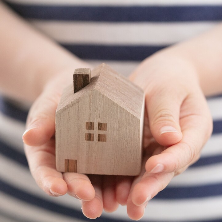 Kind hält Modellhaus in den Händen als Symbol für geerbte Immobilien
