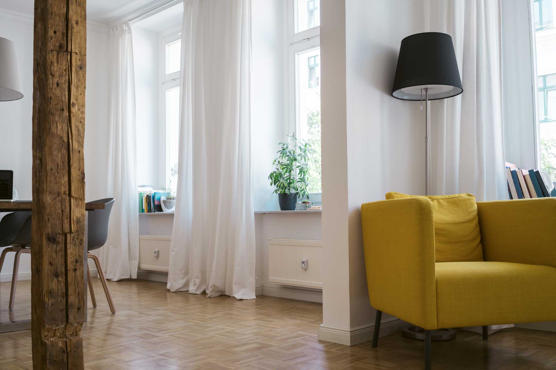 Möblierte Altbauwohnung mit hohen Decken, Holzbalken und weißen Gardinen