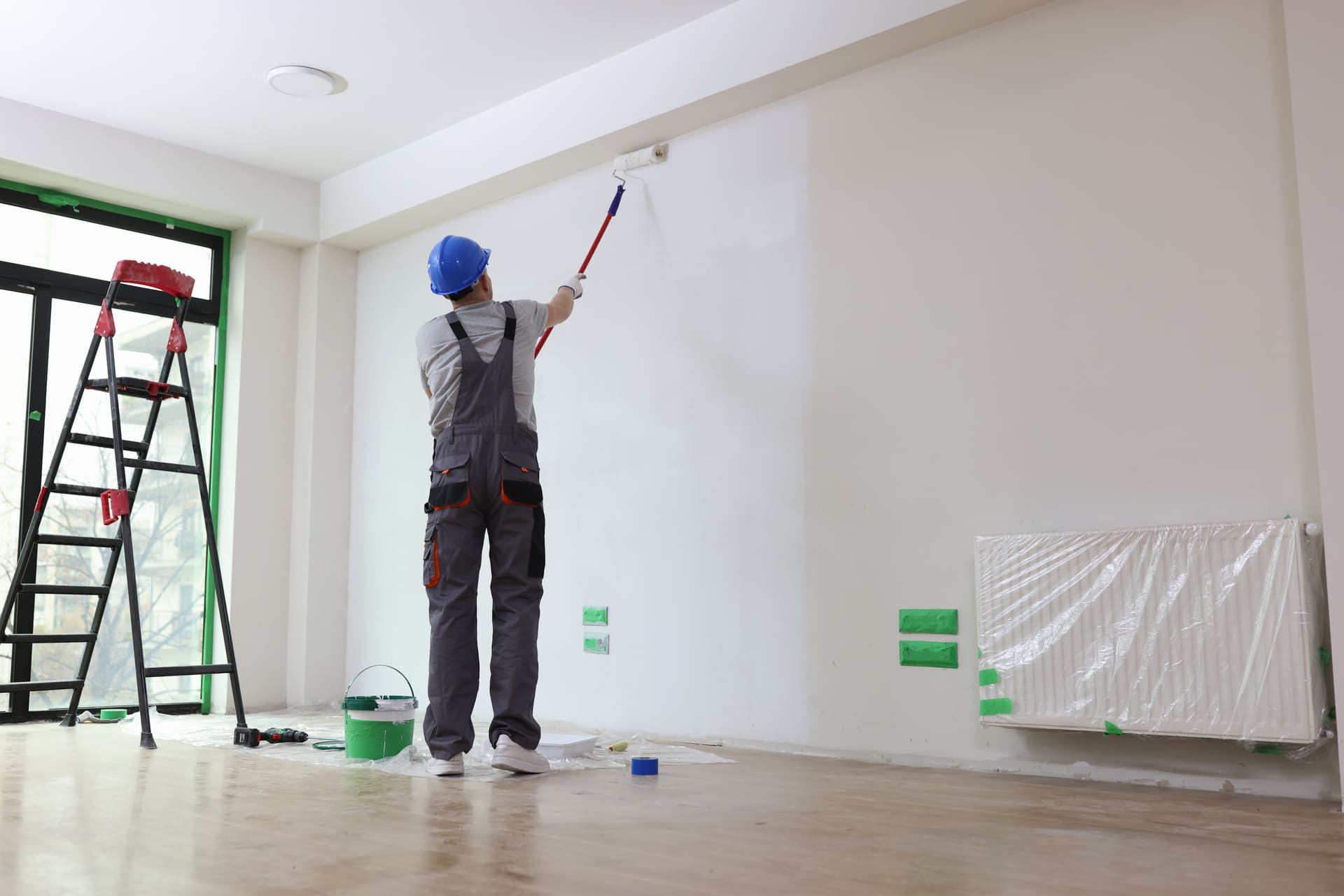 Handwerker streicht die Wand einer Wohnung bei Renovierungsarbeiten vor dem Einzug.