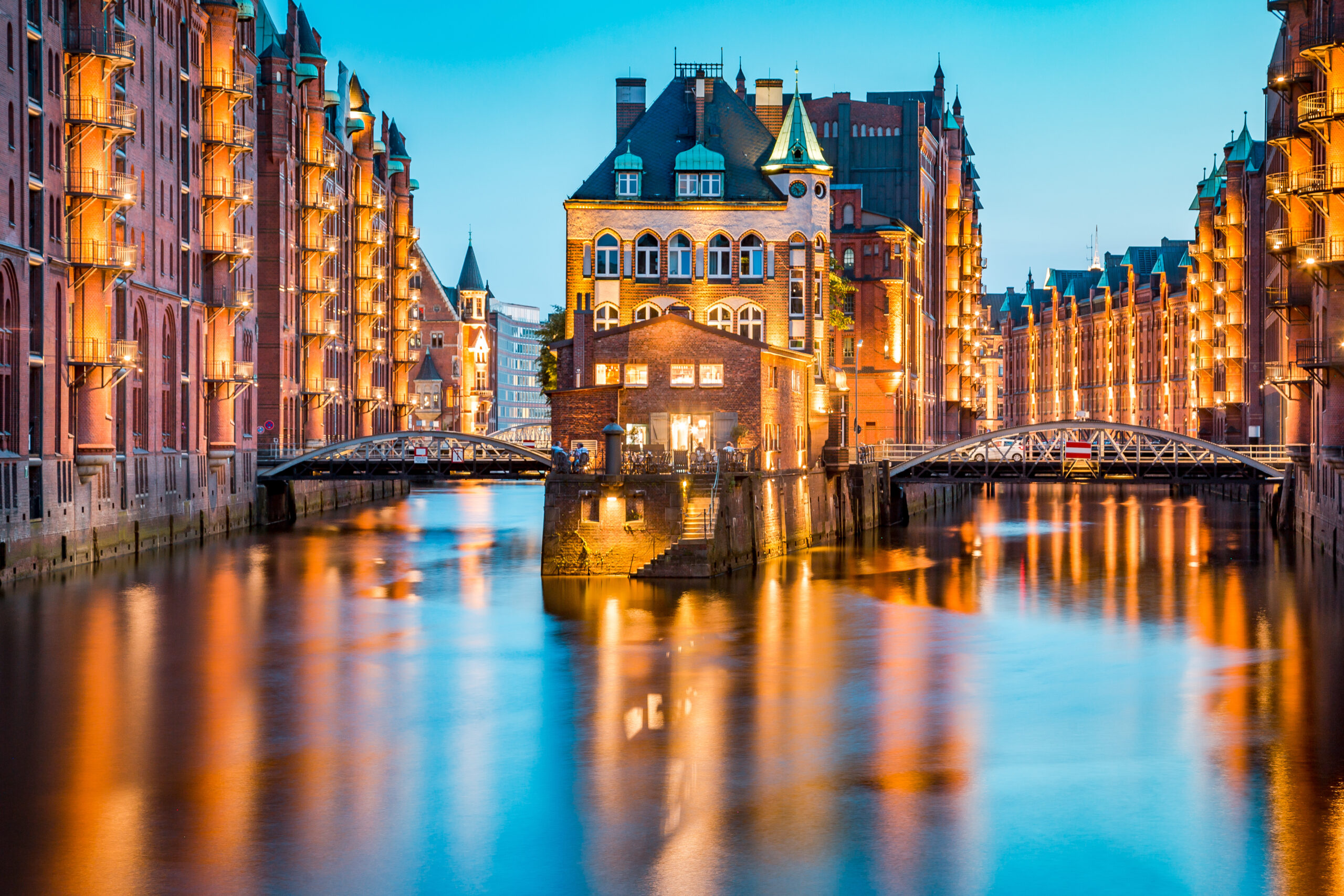 Beleuchtete Speicherstadt-Gebäude spiegeln sich im Wasser.