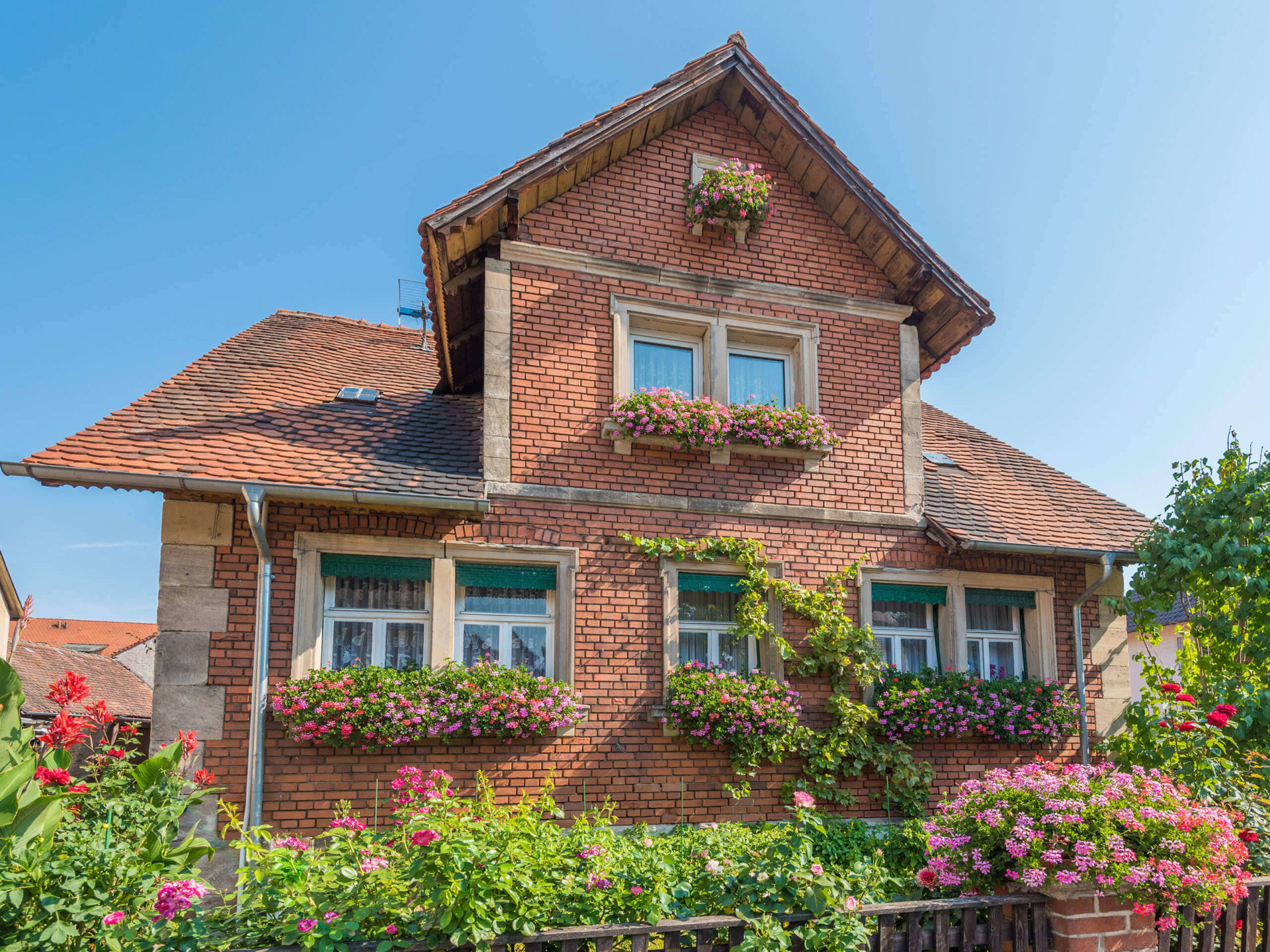 Geklinkertes Einfamilienhaus mit Blumen im Vorgarten