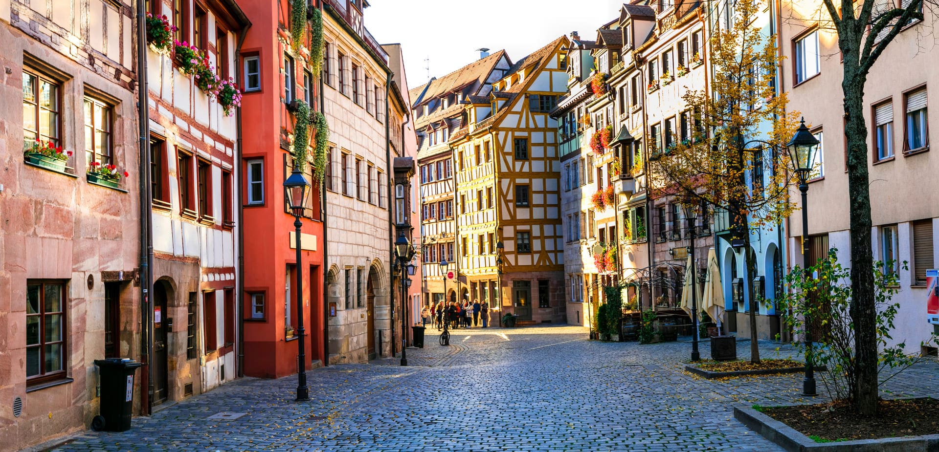Historische Fachwerkhäuser in der Nürnberger Altstadt an einer gepflasterten Straße mit Straßenlaternen.