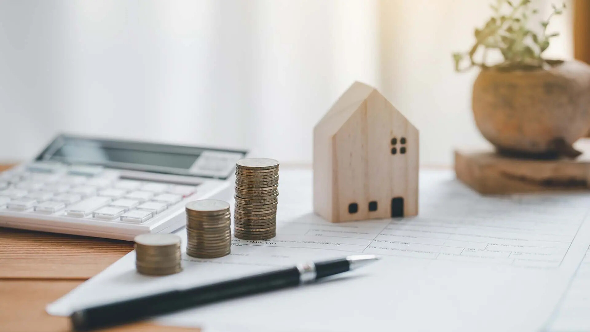 Ein Modelhaus mit Geldmünzen und Taschenrechner