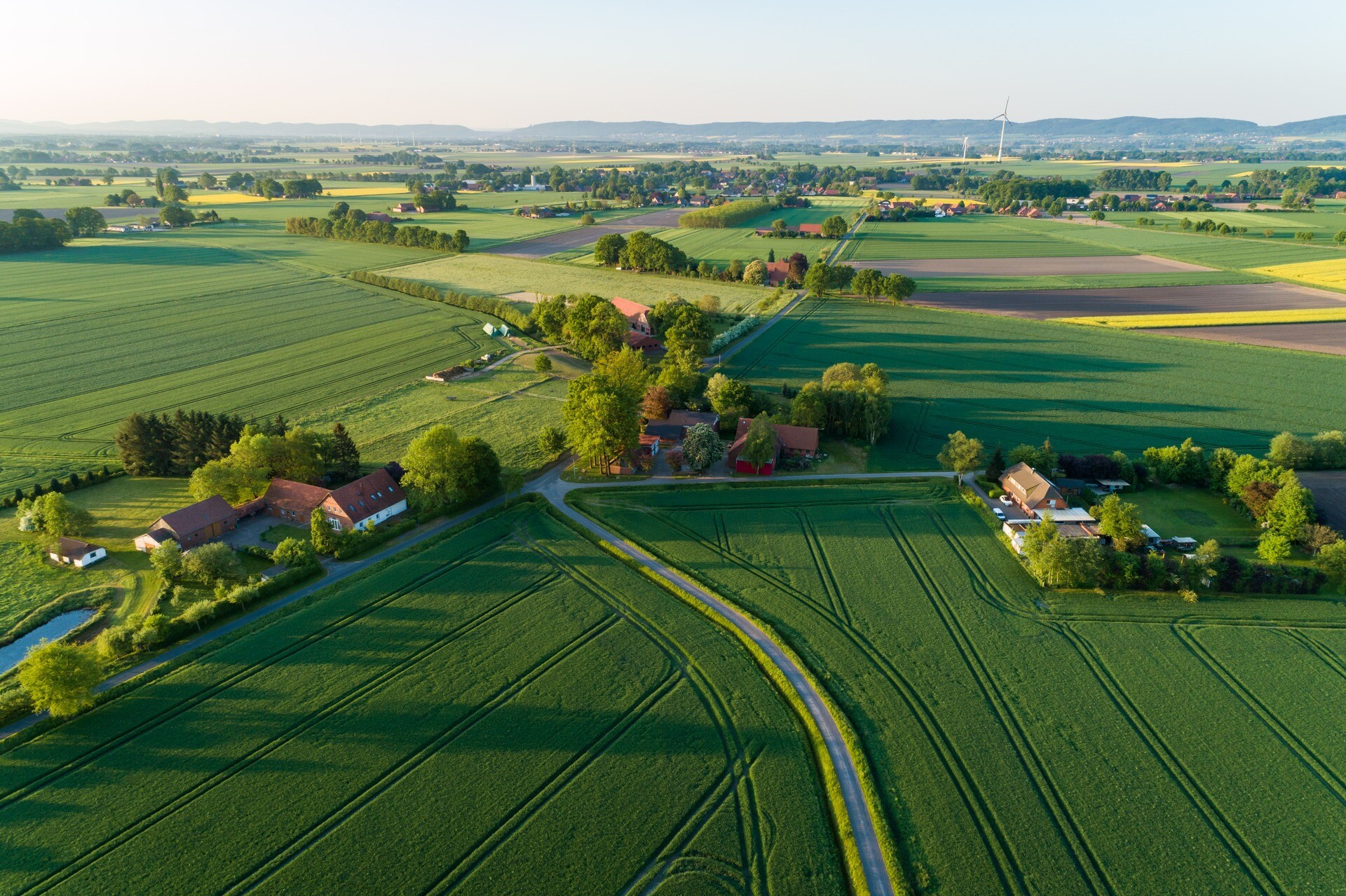 Grüne Felder, verstreute Häuser und Straßen bei Sonnenschein.