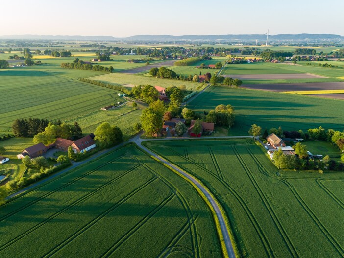 Grüne Felder, verstreute Häuser und Straßen bei Sonnenschein.