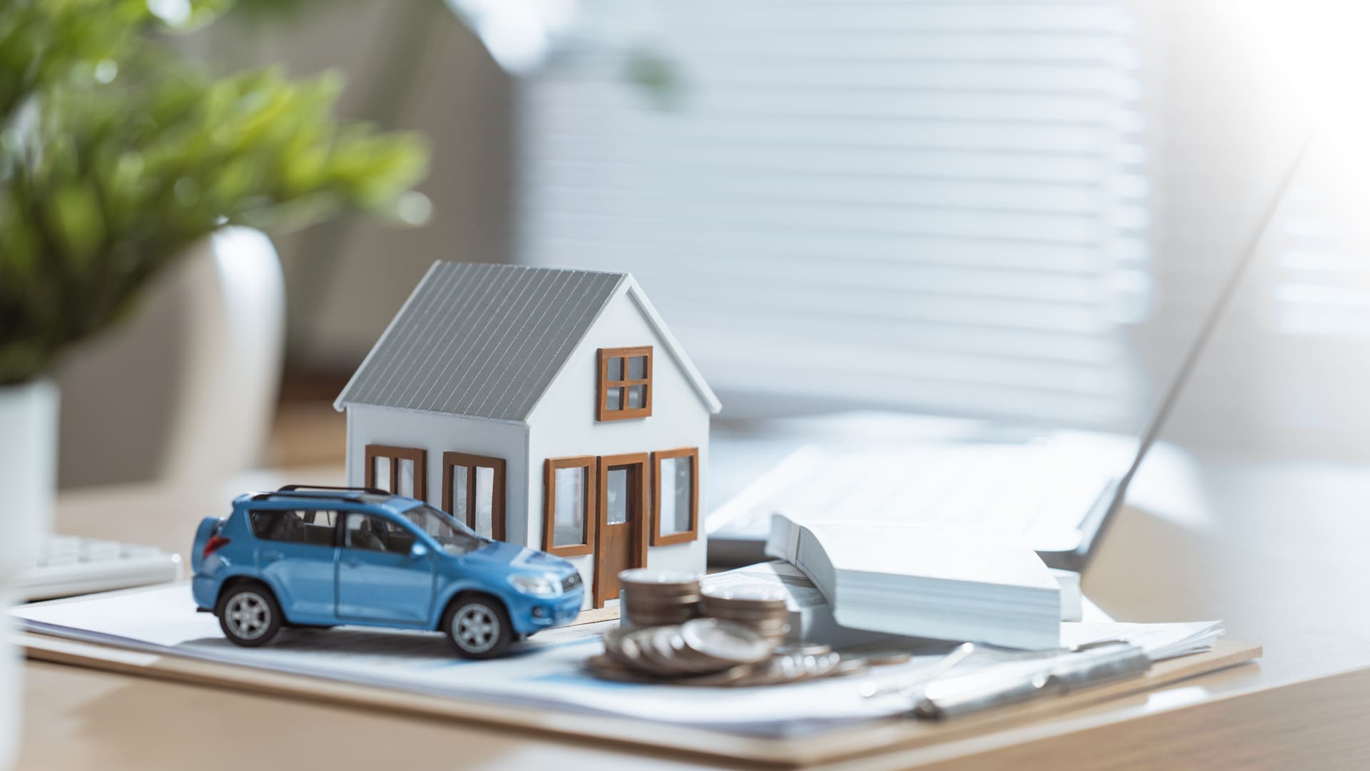 Modellhaus, Modellauto und weitere Unterlagen auf Schreibtisch