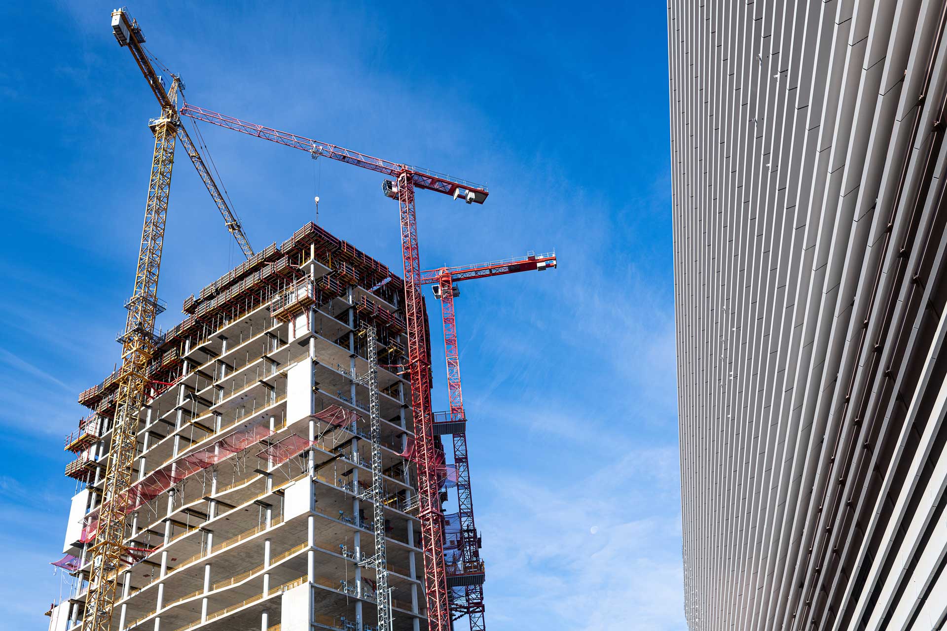 Hochhaus im Bau mit Kränen: Symbol für Bauhürden in Berlin
