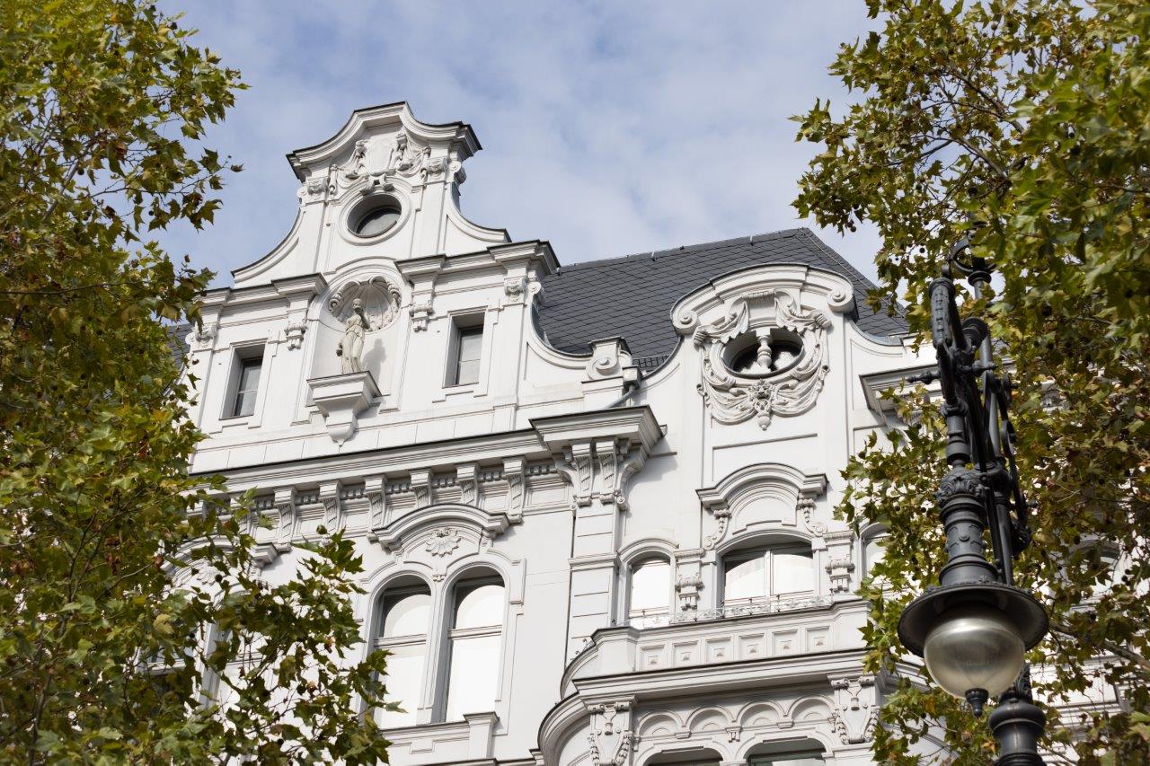 Blick auf einen weißen Altbau in Berlin zwischen Bäumen