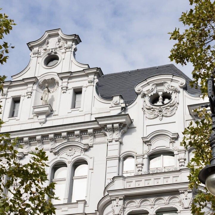 Blick auf einen weißen Altbau in Berlin zwischen Bäumen