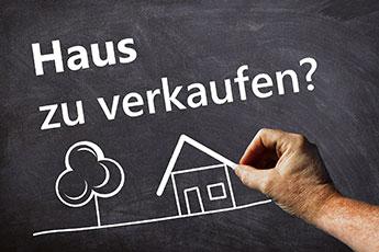 Haus, Baum und Schriftzug "Haus zu verkaufen?" mit Kreide auf Tafel gemalt