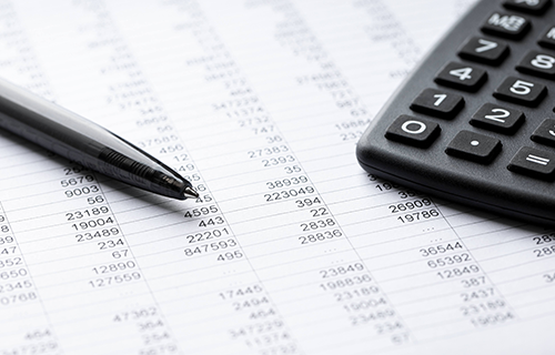 Stift, Taschenrechner auf einem Tabellenblatt mit Zahlen, symbolisiert die Wertermittlung