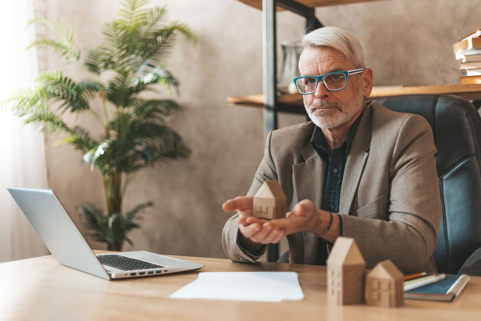 Älterer Mann hält ein kleines Haus in den Händen: Altersgerecht Wohnen