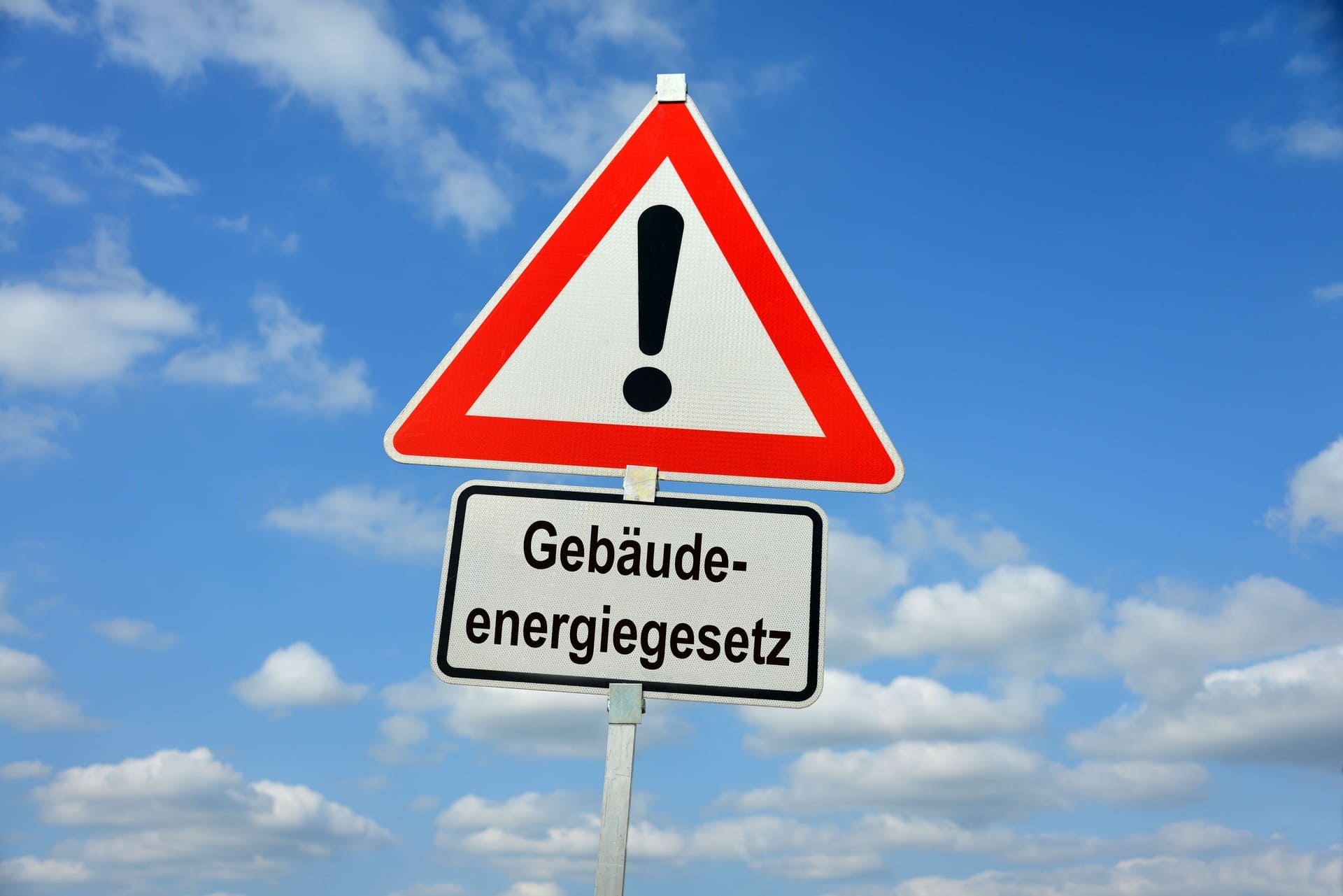 Warnschild mit Ausrufezeichen und Text Gebäudeenergiegesetz vor Himmel