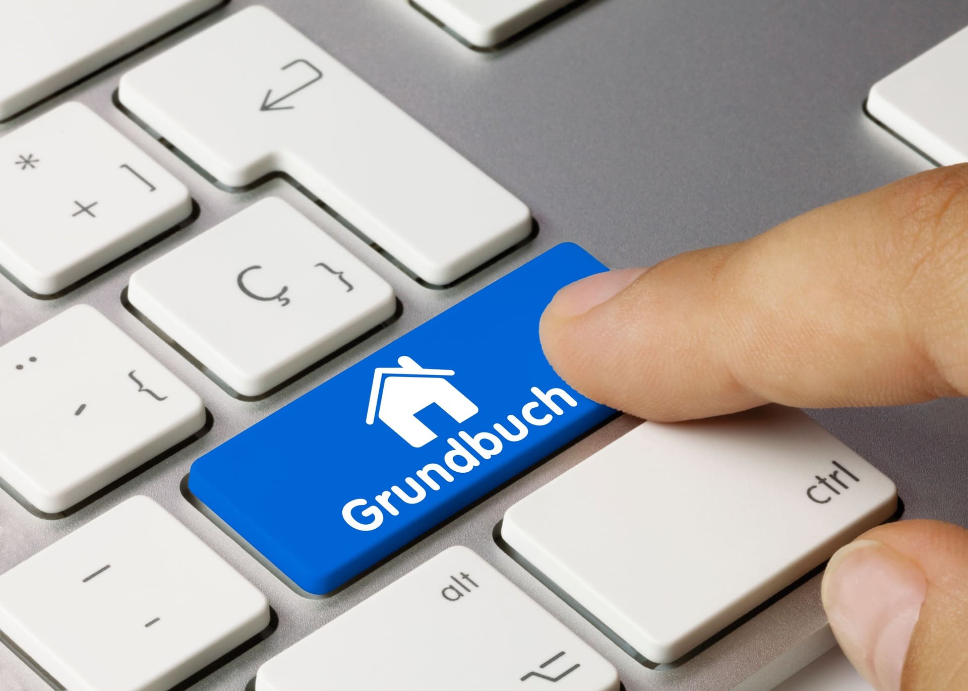 Finger auf blauer Grundbuch-Taste mit Haus-Icon auf Tastatur: Grundbuch beim Immobilienkauf