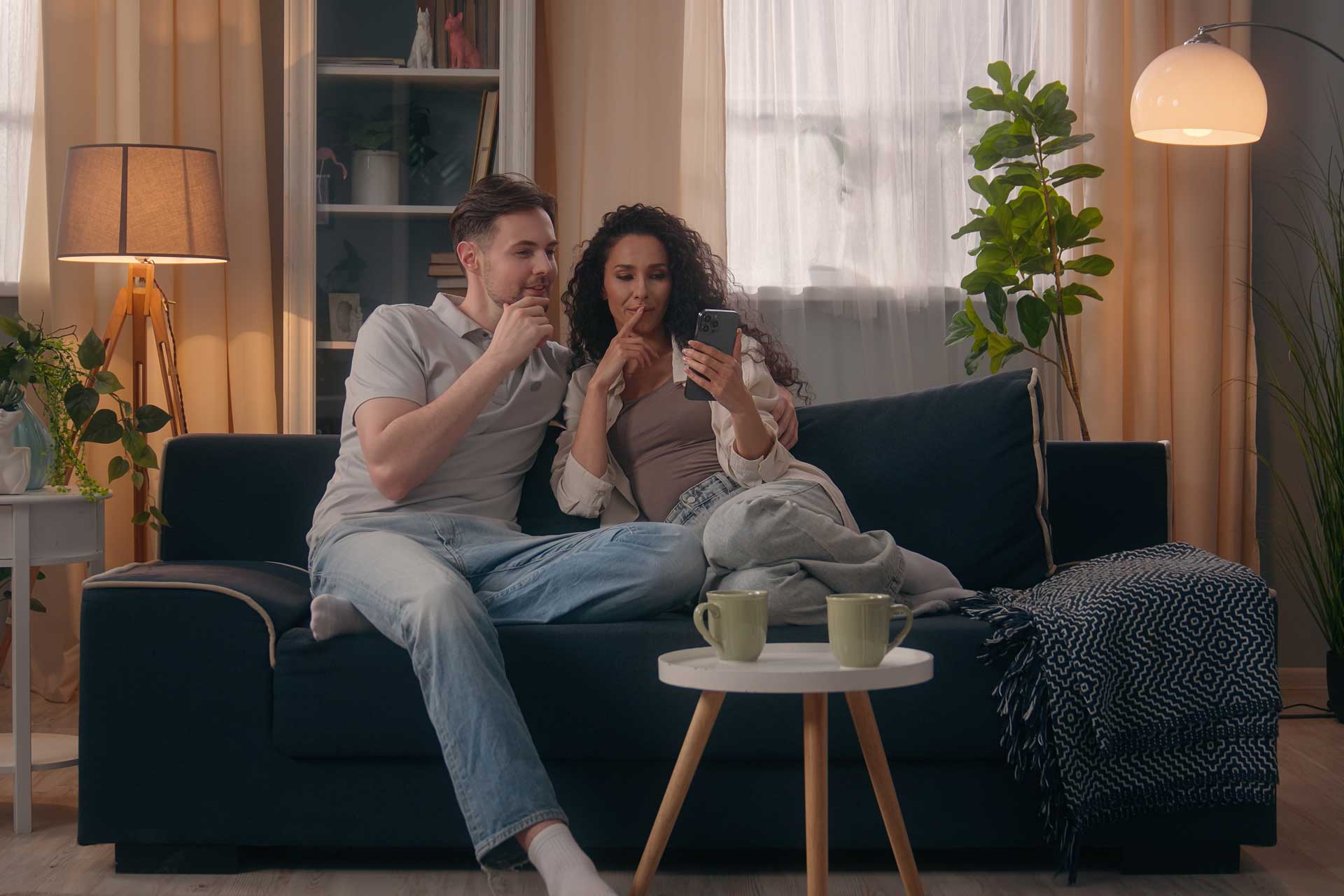 Junges Paar sucht auf der Couch nach Eigentumswohnung oder Mietwohnung