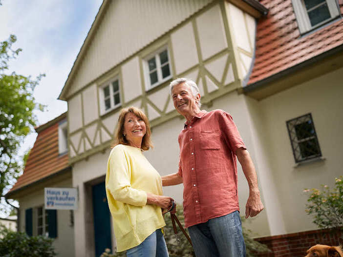 Älteres Paar steht vor einem Haus