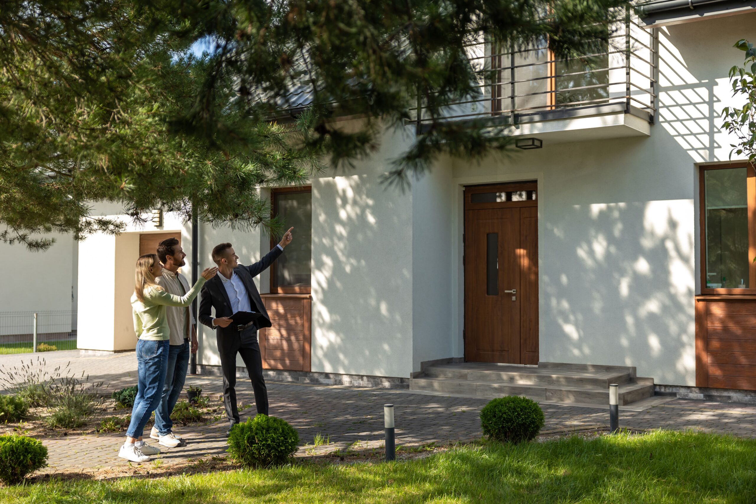 Immobilienmakler mit Kunden vor einem Haus
