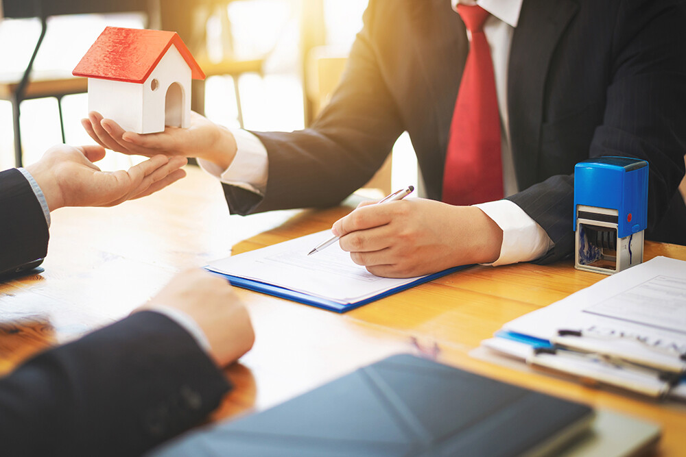 Ein Immobilienmakler berät seinen Kunden am Schreibtisch