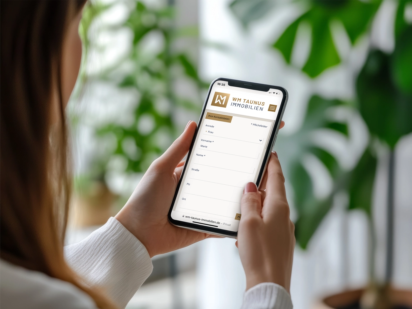 Frau betrachtet auf dem Smartphone die mobile Website eines Immobilienmaklers (WM Taunus Immobilien).