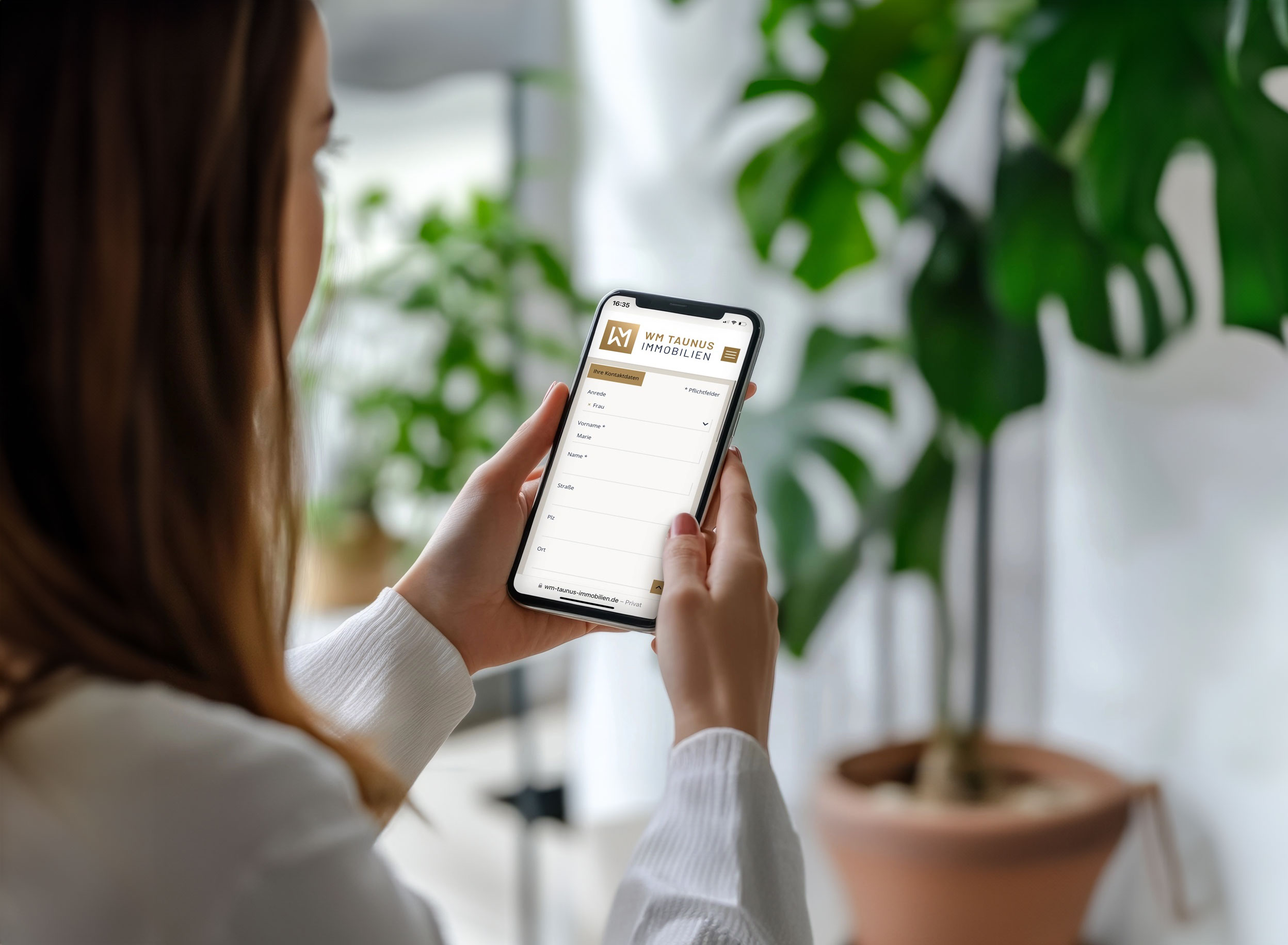 Frau betrachtet auf dem Smartphone die mobile Website eines Immobilienmaklers (WM Taunus Immobilien).