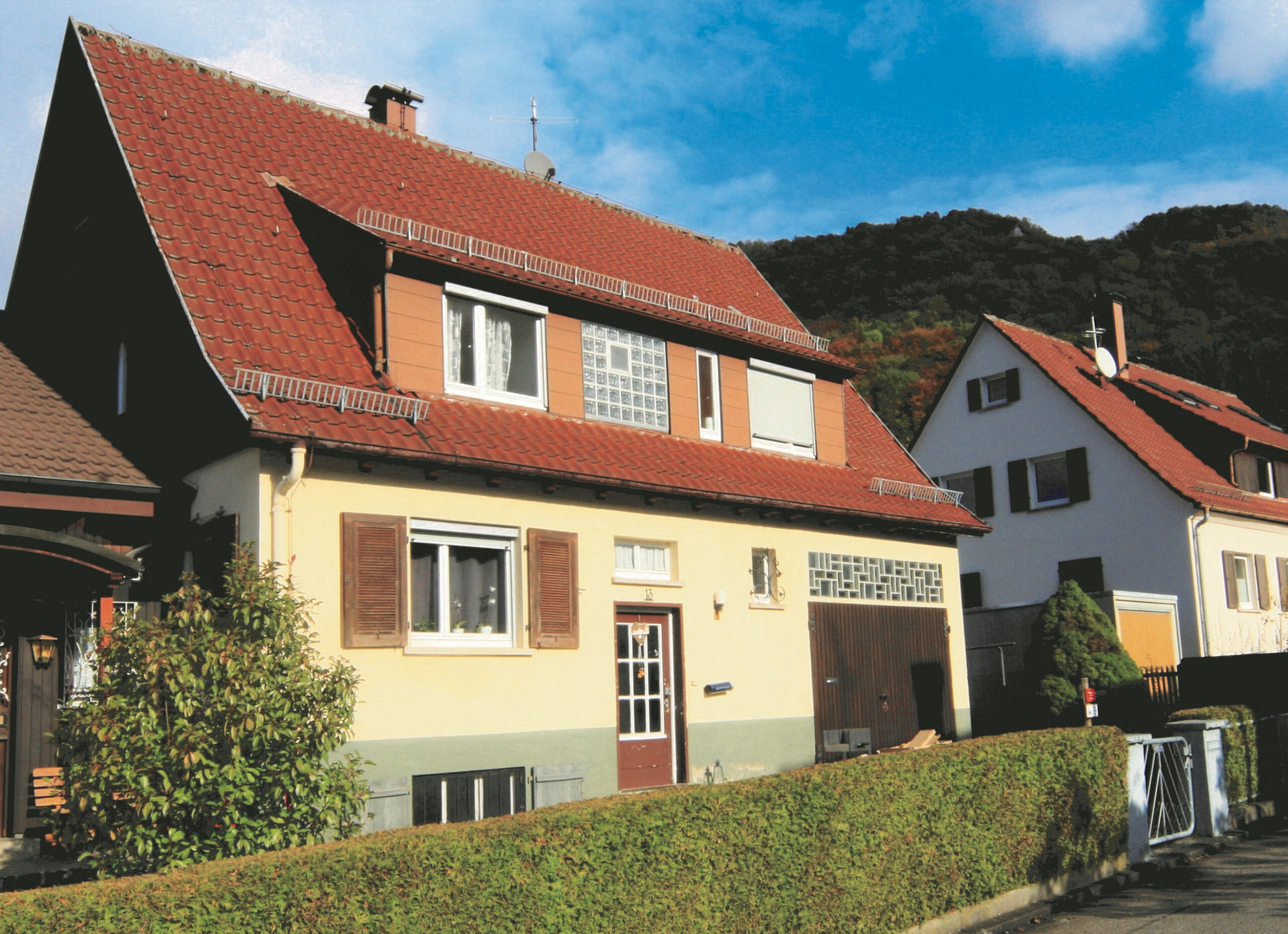 Wohnhaus mit rotem Dach und Hecke
