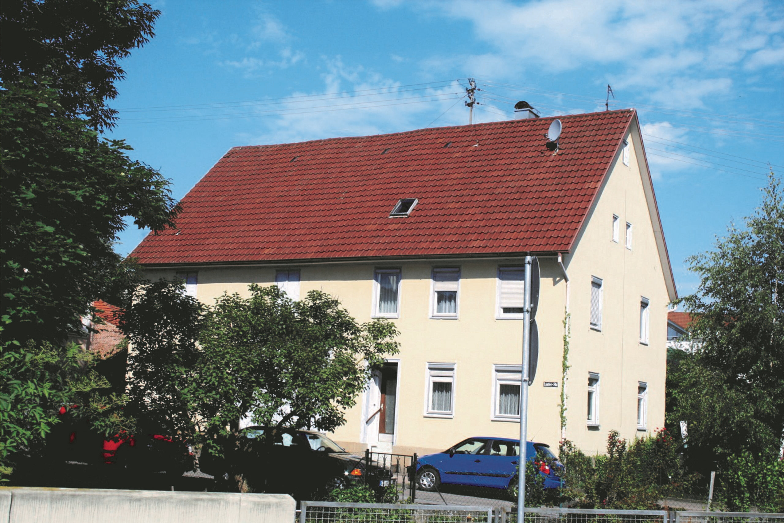 Beige Haus mit rotem Dach und geparkten Autos