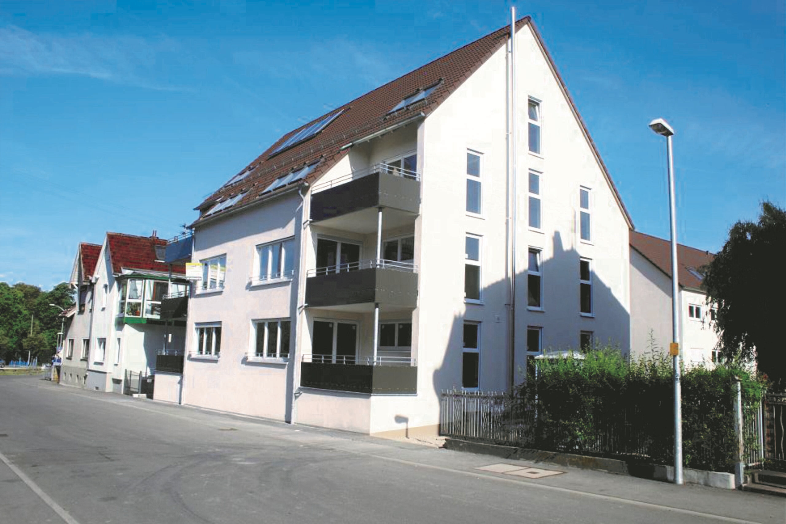 Dreistöckiges Apartmenthaus mit Balkonen, blauer Himmel