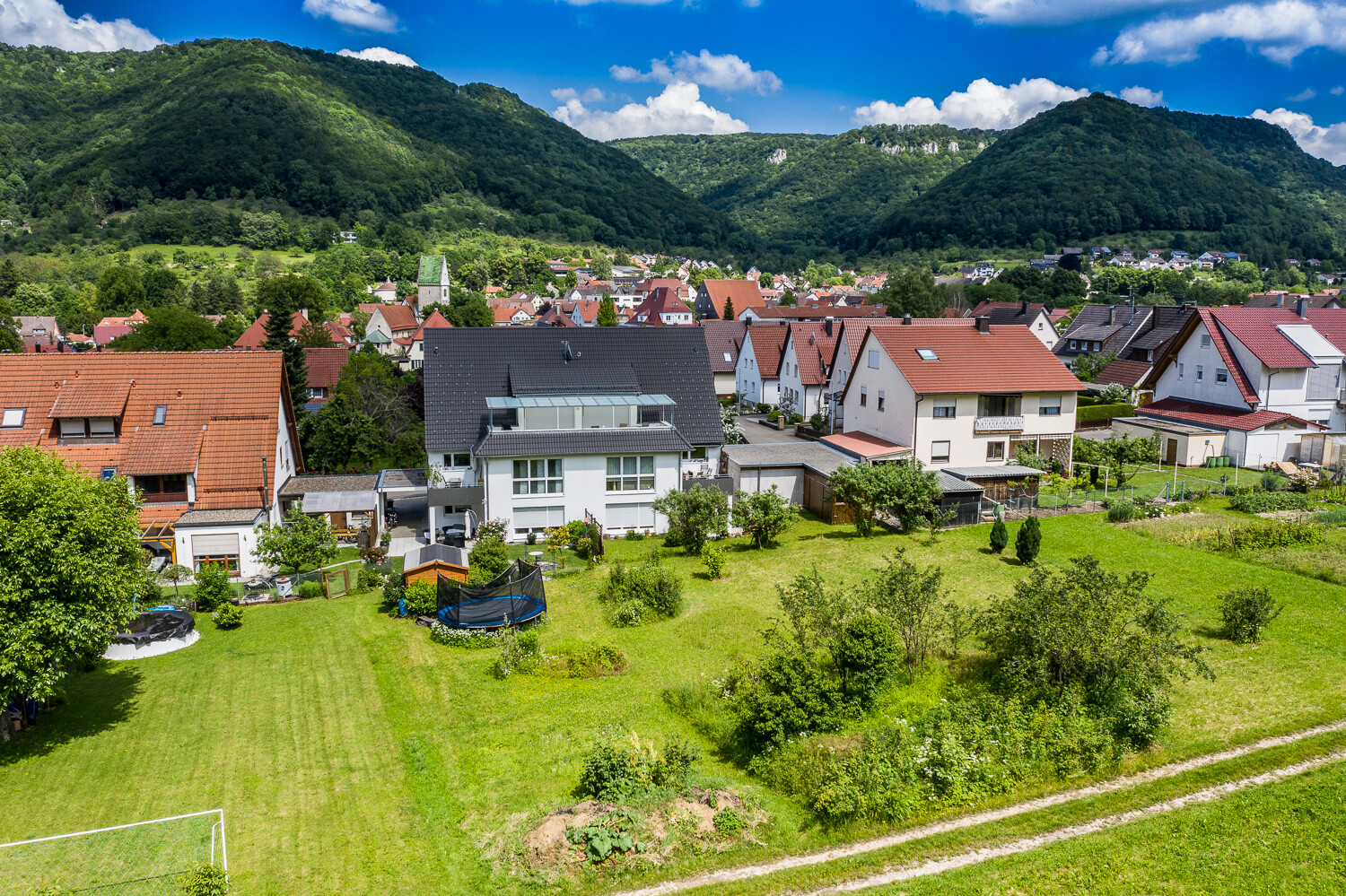 Häuser mit roten Dächern und Gärten unter blauer Himmel