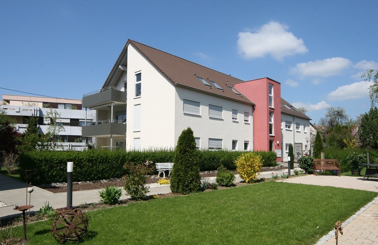 Weißes Wohnhaus, grüne Wiese, blauer Himmel