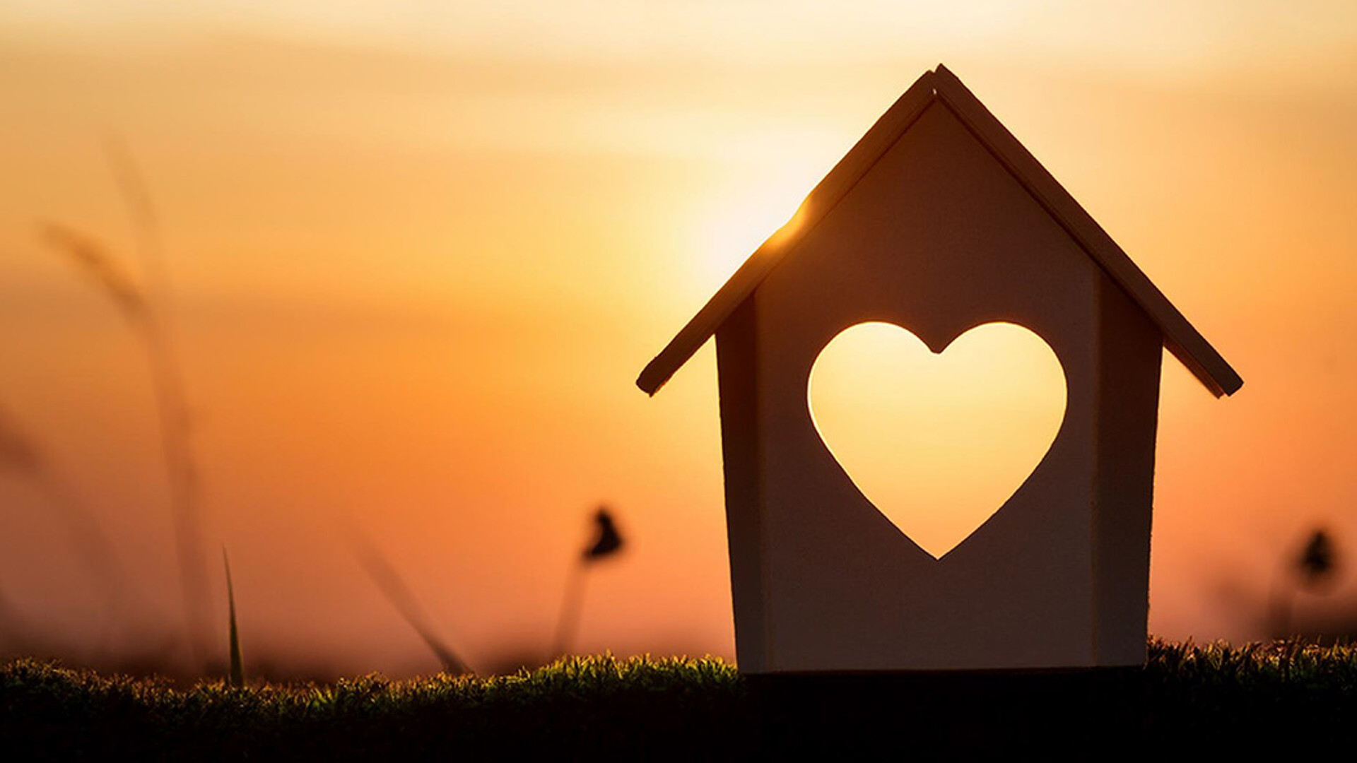 Hausmodell mit Herzausschnitt bei Sonnenuntergang