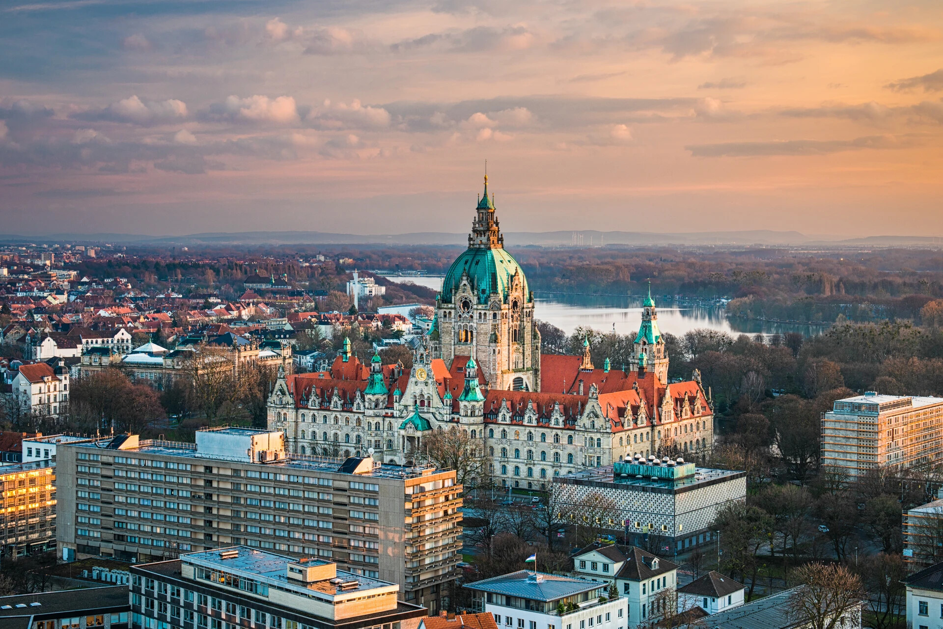 Neues Rathaus Hannover mit Fluss bei Sonnenuntergang.