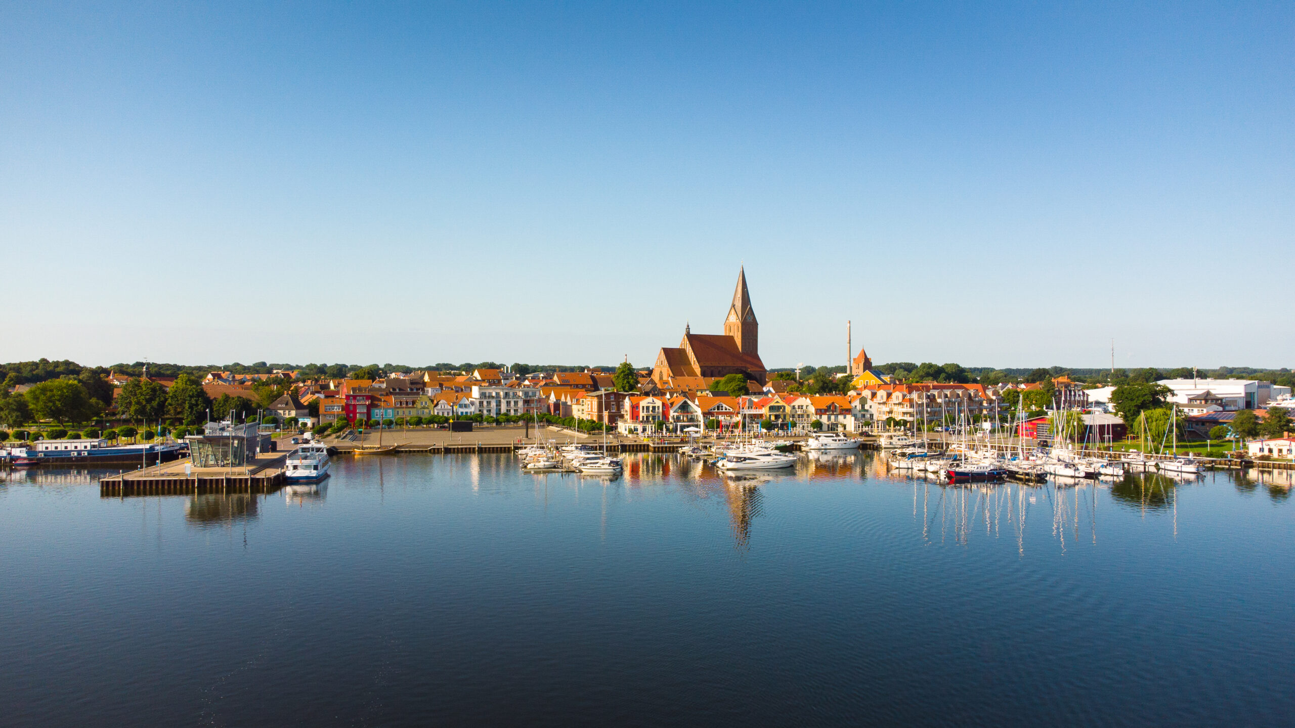 Boote in einem Hafen in der Nähe einer Stadt mit Kirchturm, blauer Himmel.