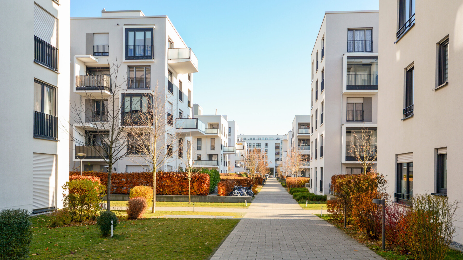 Moderne Wohnungen mit Balkonen, Grünflächen und Gehweg.