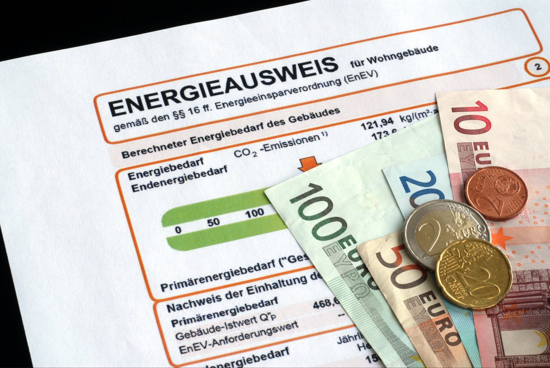 Energieausweis für ein Wohngebäude mit Euro-Scheinen und Münzen.