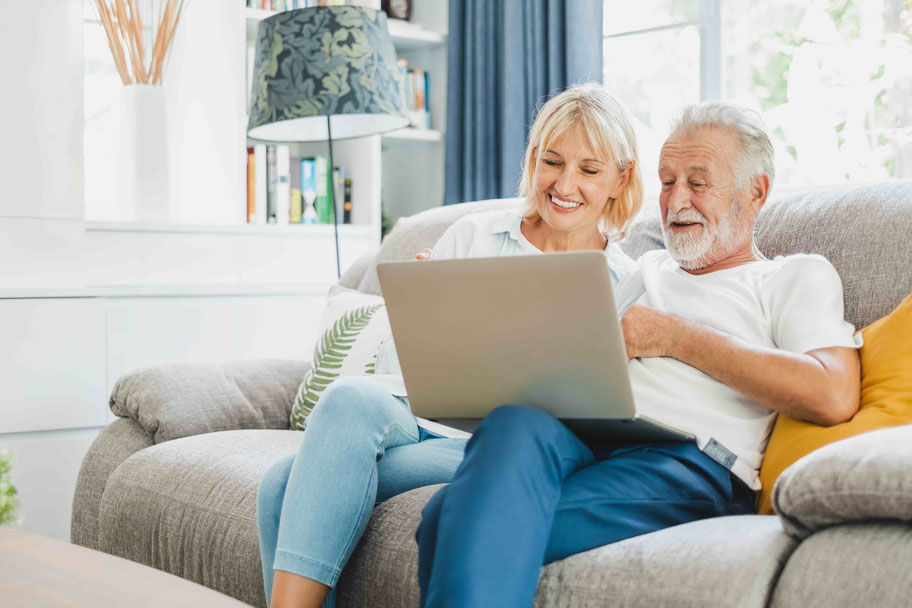 Älteres Ehepaar mit Laptop auf dem Sofa