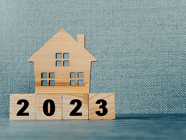 Holzhaus und Holzwürfel mit der Zahl 2023