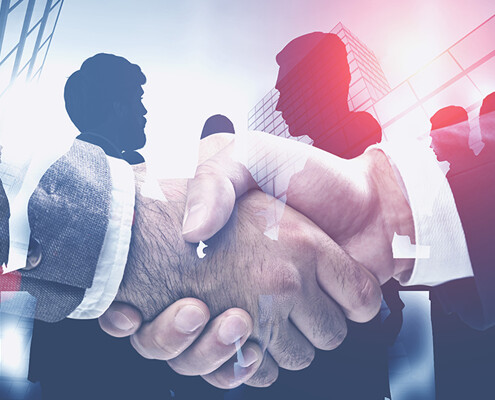 Handschlag, im Hintergrund Businessleute