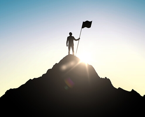 Mann auf Gipfelspitze mit Flagge
