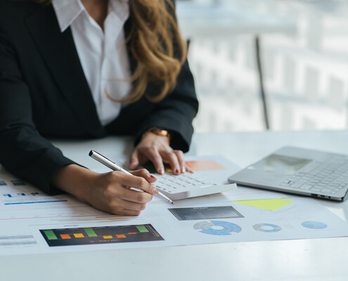 Frau mit Taschenrechner und Laptop bei der Auswertung von Statistiken