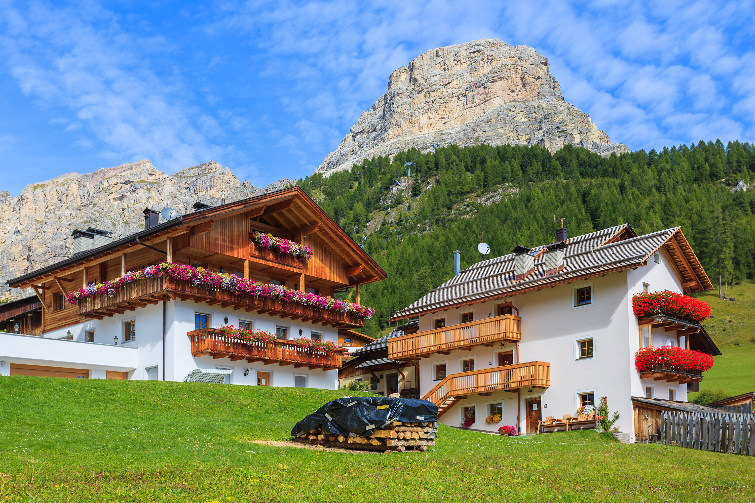 Traditional alpine houses with flowers on balcony in summer landscape of Dolomites Mountains (The Alps), Italy