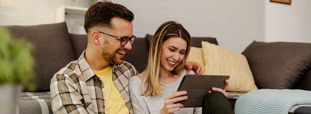 Junges Paar liest auf dem Tablet Tipps zur Immobiliensuche