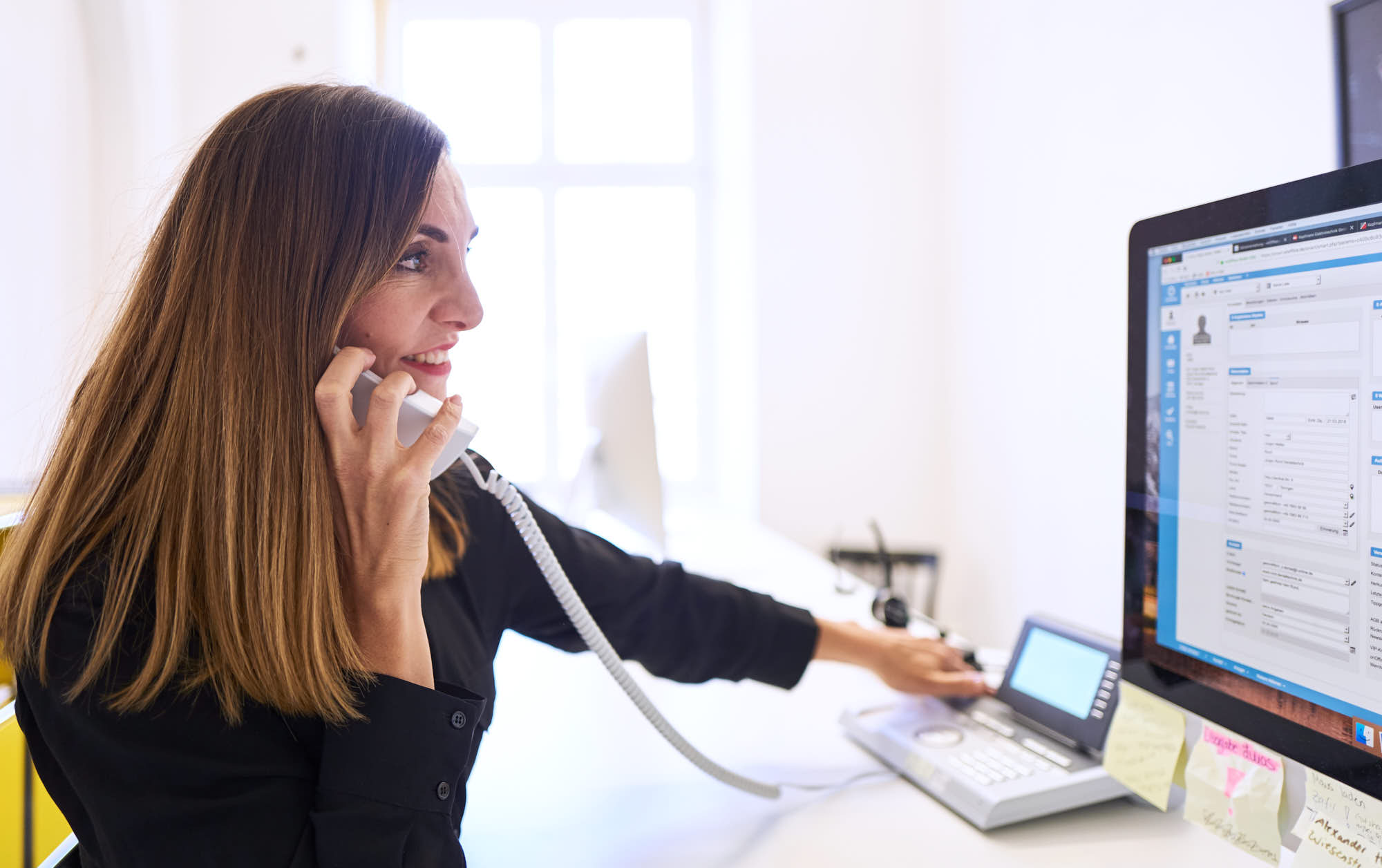 Mitarbeiterin beim Telefonieren am PC