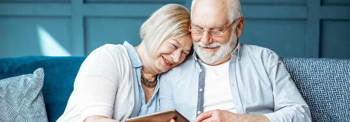 Seniorenpaar auf der Couch mit Tablet