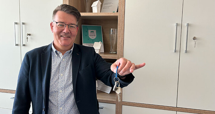 Dirk Schlösser mit Schlüssel in seinem Büro: Ihr guter & lokaler Makler