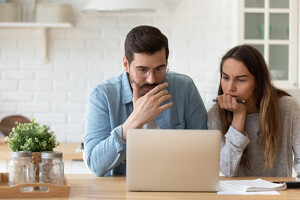 Paar informiert sich am Laptop über die Fehler beim Immobilienkauf