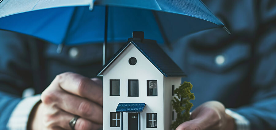 Person schützt Haus mit einem kleinen Regenschirm als Symvol für Versicherungen