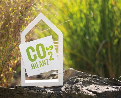 Holzrahmen in Hausform mit Schild "CO2 Bilanz"